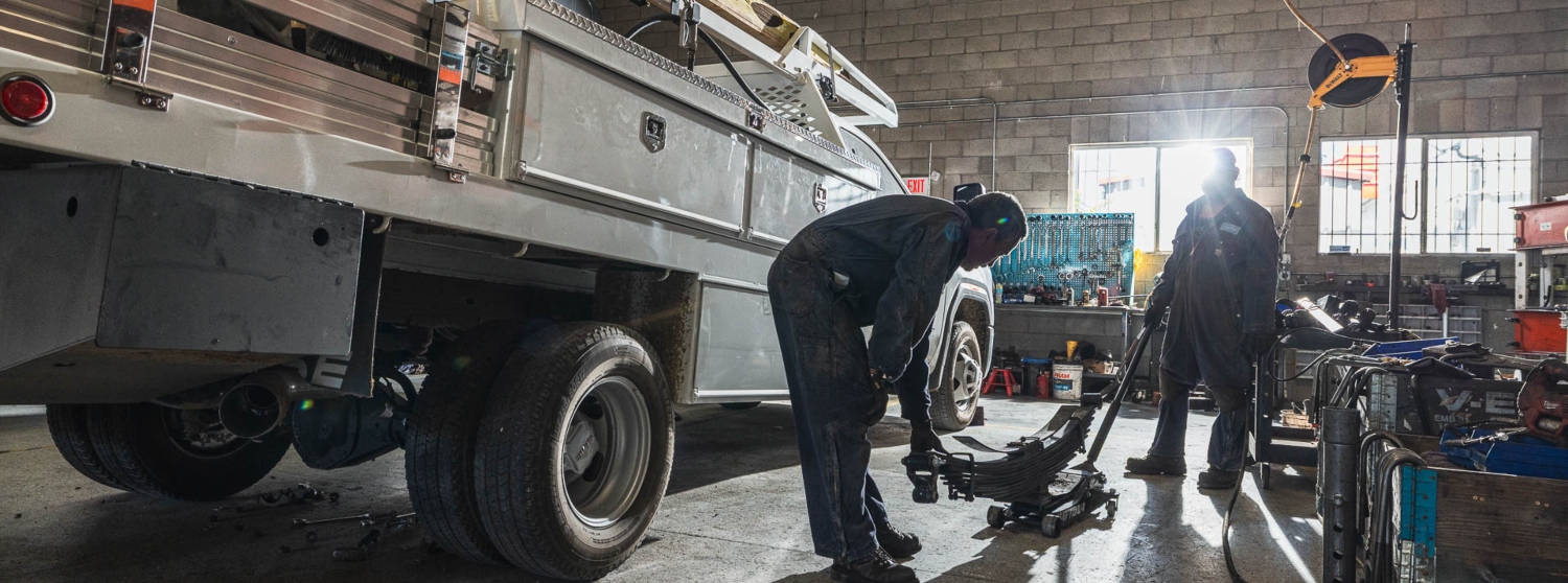 Mechanics at John's Spring and Suspension replace a leaf spring on a work truck